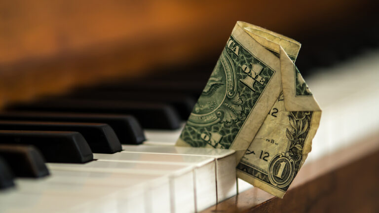 piano med en pengeseddel i mellom knappene